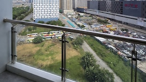 Vista desde un balcón con cielo despejado, que muestra un estacionamiento, varios edificios y una carretera.