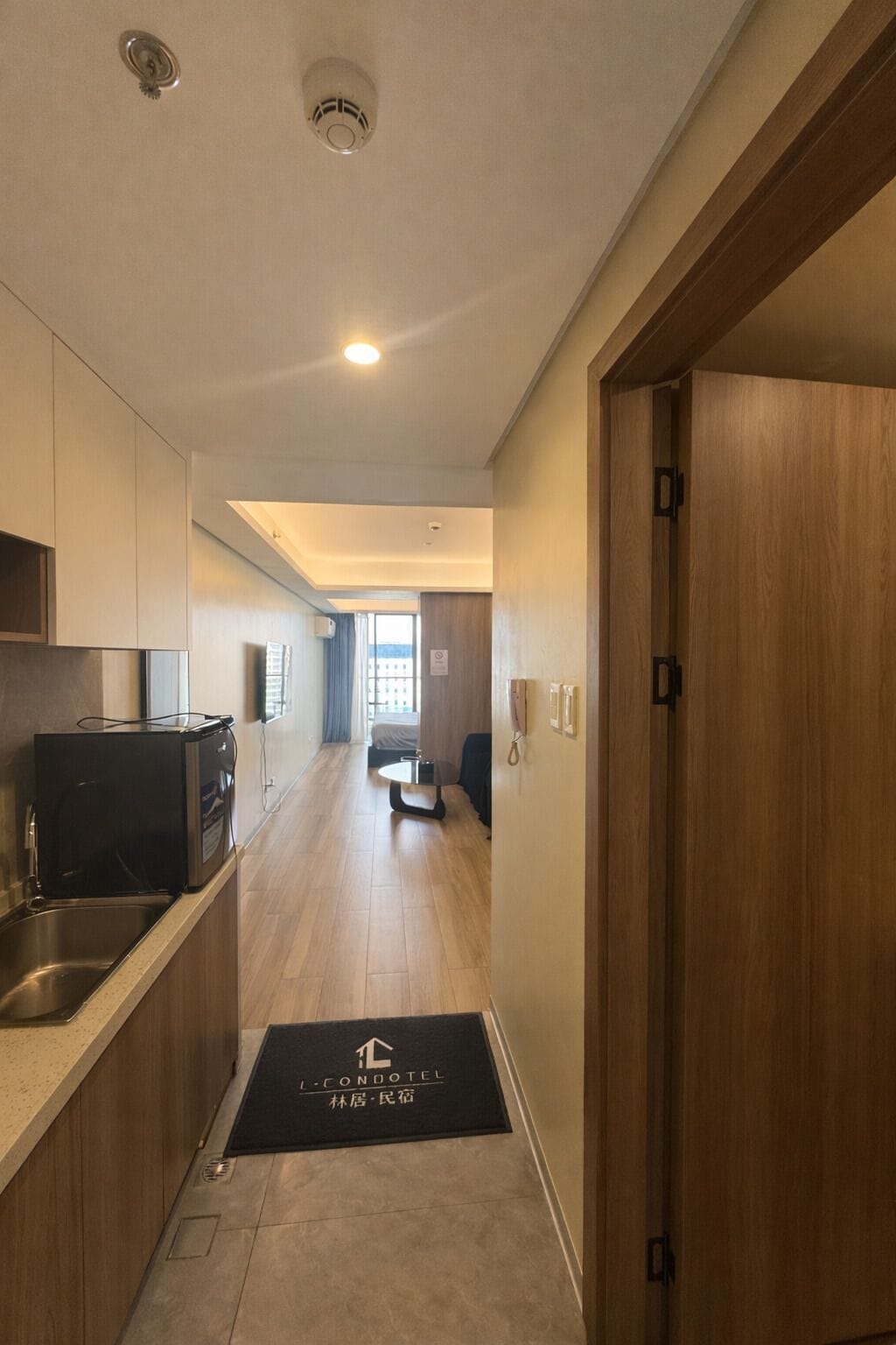 A modern hotel corridor with a kitchenette, a dining area, and a view to the outside.