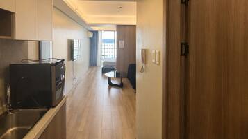 A modern hotel corridor with a kitchenette, a dining area, and a view to the outside.