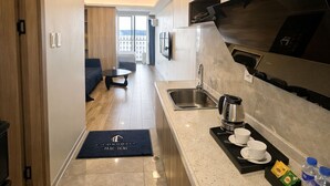 A modern kitchen with a stainless steel sink, a coffee maker, and a tray with cups and a bottle. - L.CONDOTEL(Imperial Plaza Residence) (Parañaque)