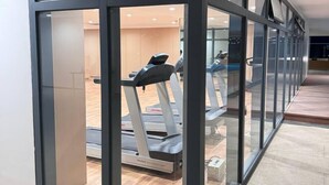 Un gimnasio moderno con paredes de vidrio, cintas de correr y piso de madera.