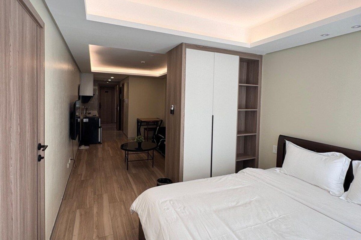A hotel room with a bed, wardrobe, desk, and a small seating area.