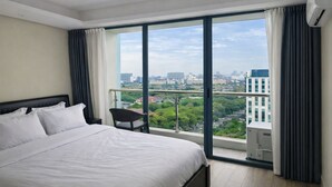Habitación de hotel con una cama grande, una silla y un balcón con vista a la ciudad.