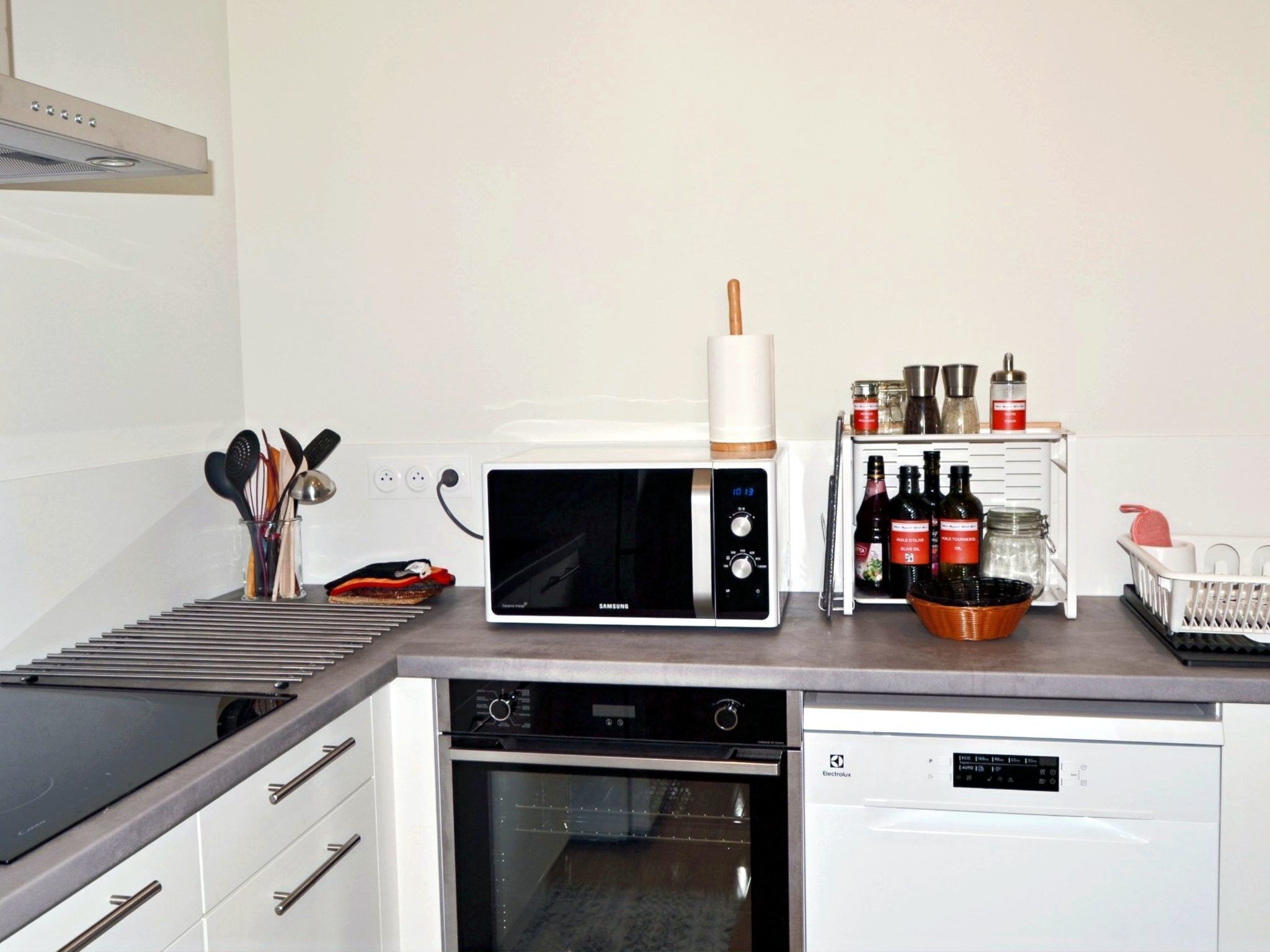 A modern kitchen with a microwave, oven, and a small refrigerator.