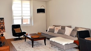 A living room with a sofa, a coffee table, a chair, and a lamp.