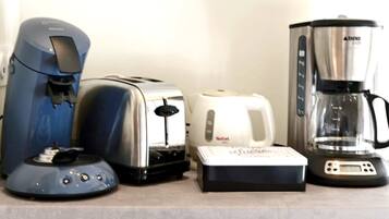 Eine Küchenarbeitsplatte mit einer blauen Kaffeemaschine, einem Toaster, einem weißen Wasserkocher und einer Kaffeekanne.