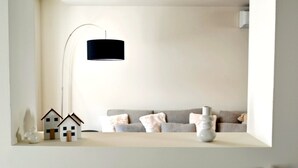 A minimalist living room with a sofa, a lamp, and small house models on a table.