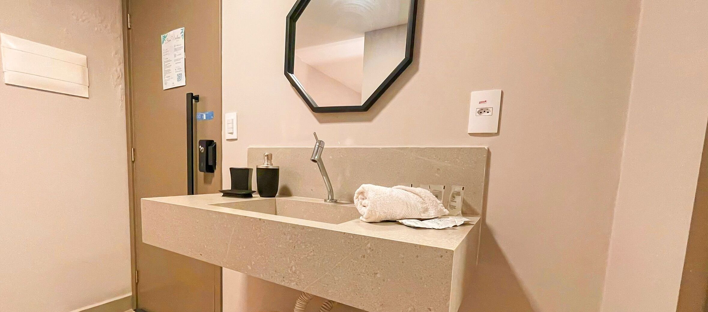 A bathroom with a sink, mirror, towel, and toiletries.