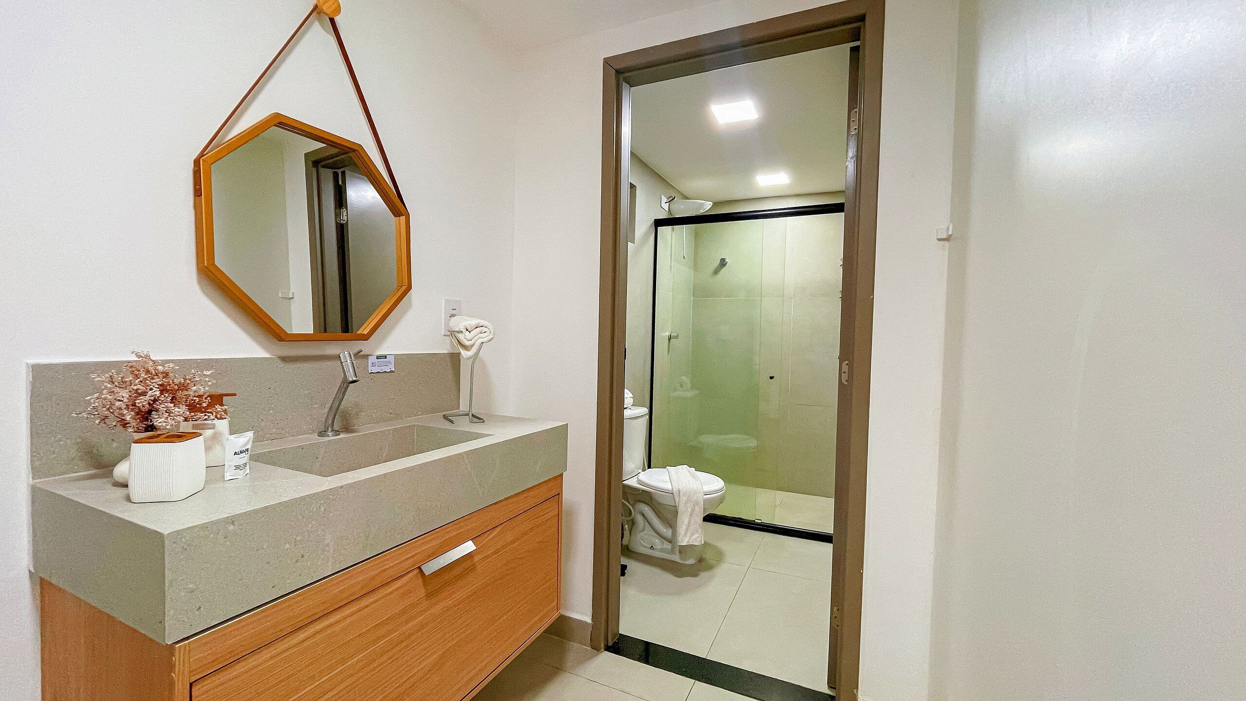 A bathroom with a wooden vanity, a mirror, a sink, and a toilet.