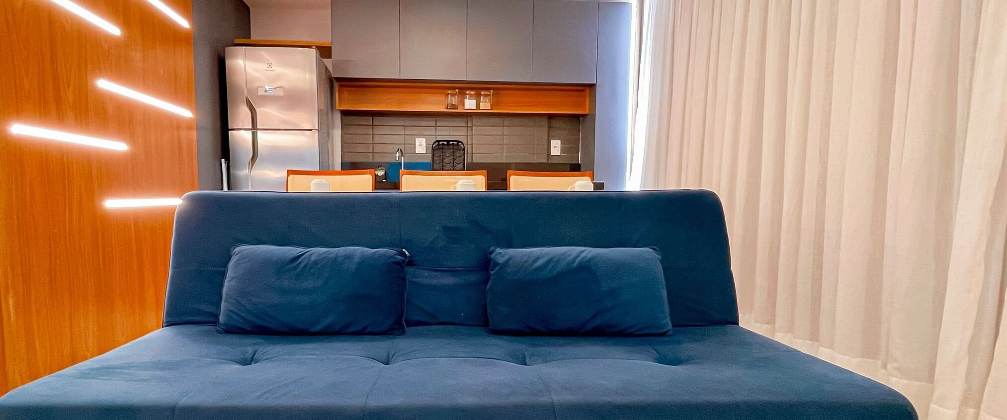 A modern living area with a sofa and a kitchen in the background.