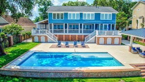 Ein zweistöckiges Haus mit großem Garten, inklusive Swimmingpool, überdachter Terrasse und Ziegelsteinfassade.