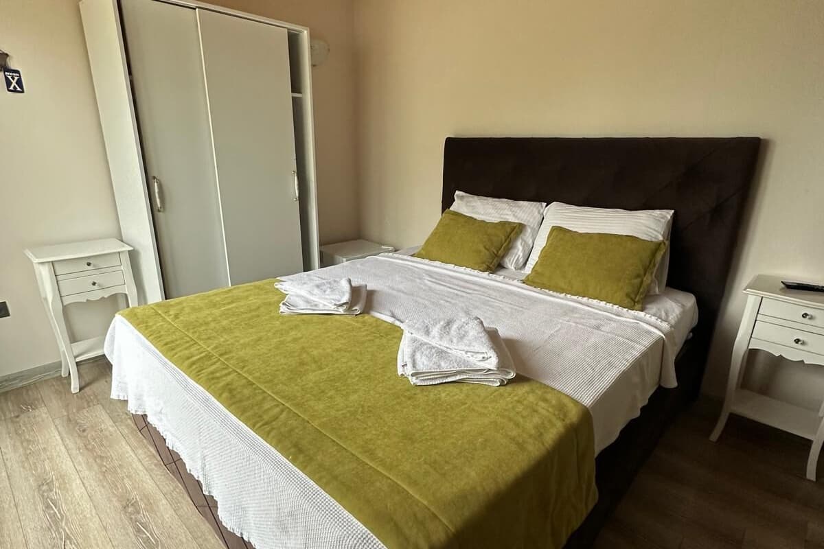 Un dormitorio con cama, armario, mesita de noche y suelo de madera.