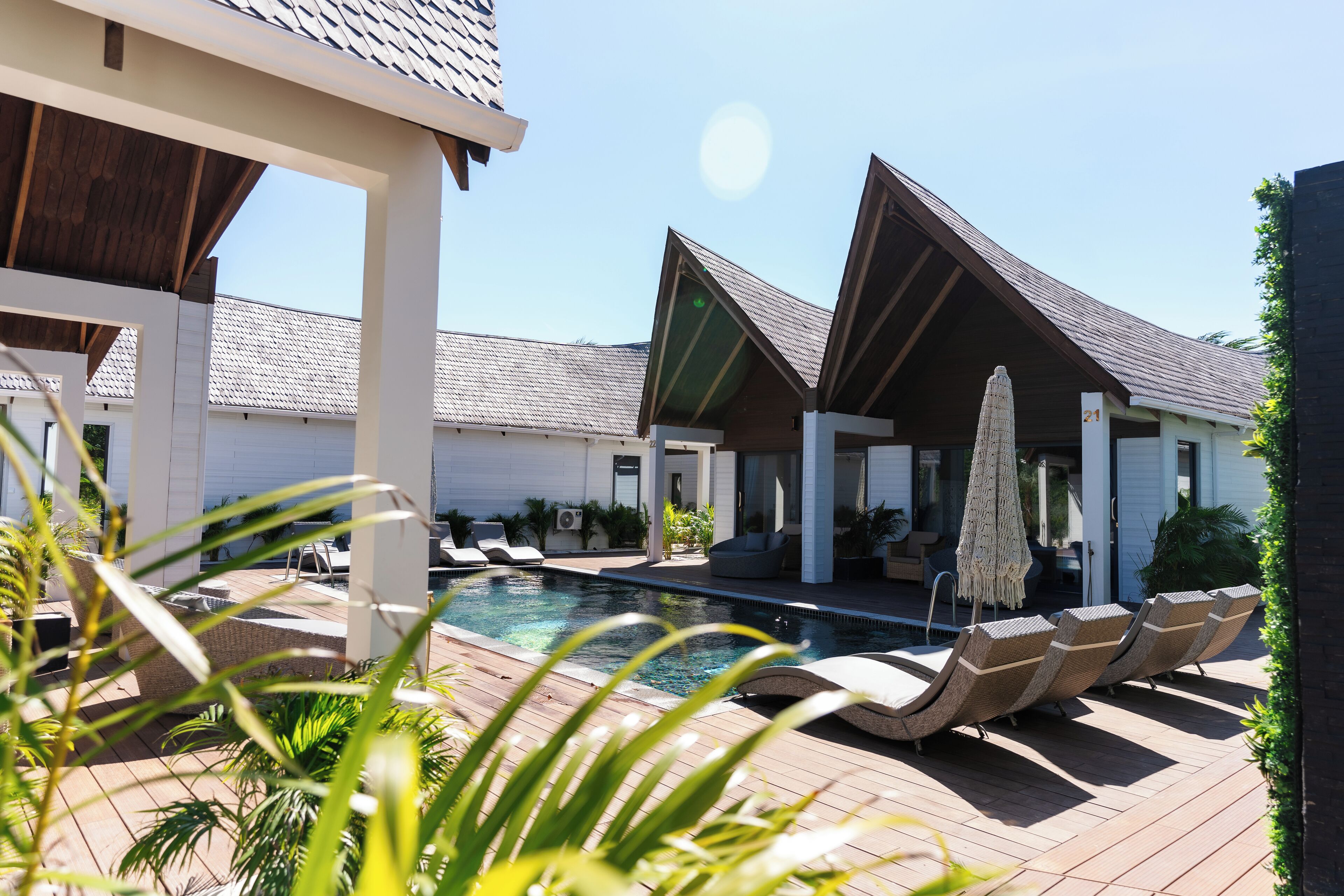 A pool area with lounge chairs and umbrellas, surrounded by buildings with a modern design.