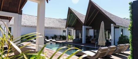 A pool area with lounge chairs and umbrellas, surrounded by buildings with a modern design.