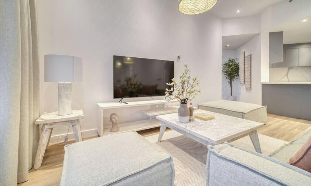 Un salon moderne avec un téléviseur à écran plat, une table basse agrémentée d’objets décoratifs et un canapé.