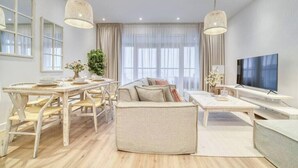 A modern living room with a sofa, dining table, chairs, and a TV.