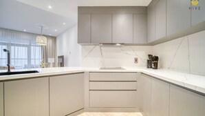 A modern kitchen with a built-in oven, a sink, and a window with curtains.