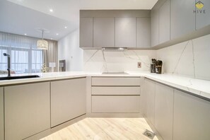 A modern kitchen with a built-in oven, a sink, and a window with curtains. - Palm Jumeirah Apt w/ Beach Access & Sea View (Dubai)