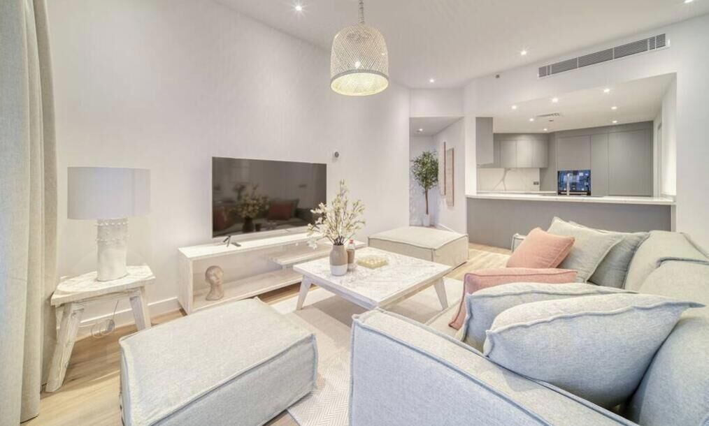 A modern living room with a sofa, coffee table, TV, and a pendant light.
