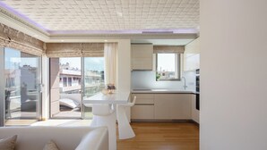 A modern kitchen with a white countertop, built-in cabinets, and a window overlooking the city. - DeMaNi President Suites (Sitia)