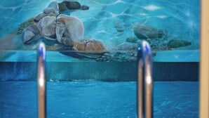 A painting of a serene beach scene with rocks and water. - DeMaNi President Suites (Sitia)