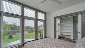 Une chambre avec une grande fenêtre, un lit et un dressing.