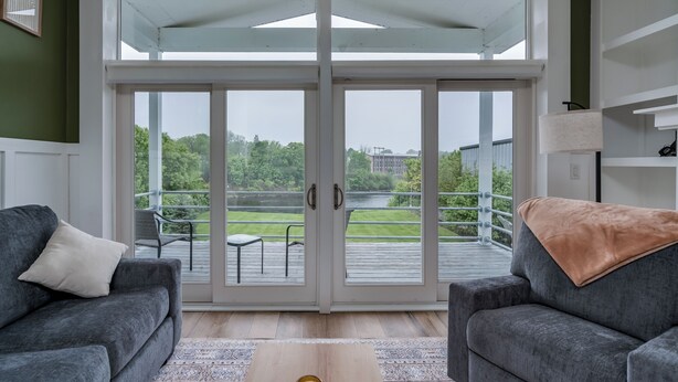 Un salon moderne doté d’une grande porte-fenêtre coulissante donnant sur une terrasse extérieure.