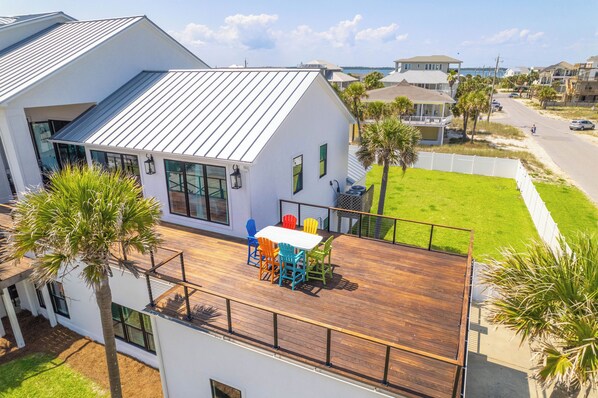 A modern house with a wooden deck, large windows, and a view of the ocean. - 20ft Beach Access, Sleeps 31, Pool, Bikes, Basketball,Ping Pong,2 Kitchens, Pets (Pensacola Beach)