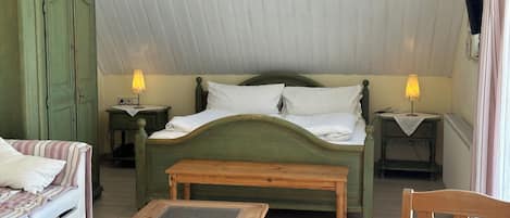 Ein Schlafzimmer mit einem Bett, zwei Nachttischen mit Lampen, einem Holzstuhl, einem kleinen Tisch und einem grünen Kleiderschrank.