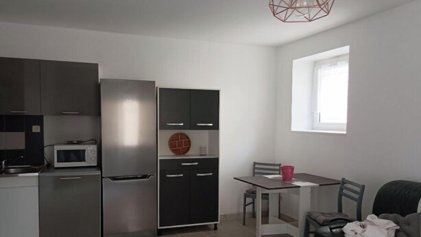 Eine kleine Küche mit Kühlschrank, Mikrowelle und einem Essbereich mit Tisch und Stühlen.