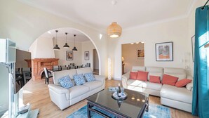 A modern living room with a fireplace, two sofas, a coffee table, and a dining area with chairs and a brick wall. - Haut de Villa 6 Personnes Juan les Pins Résidentiel Proche Plage (Antibes)