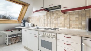 A modern kitchen with white cabinets, a gas stove, and a window above the sink. - Alpen-hostel Südgrat 8, Buxacher Straße 23 mit Motorradvermietung (Memmingen)