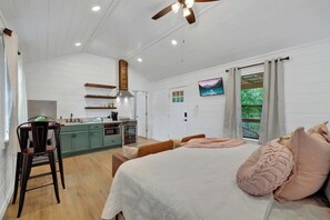 Una habitación amplia con una cama grande, un comedor y una cocina.