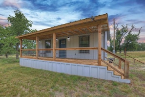 A single-story wooden structure with a covered porch, a staircase, and a fenced area. - Cates Cottage-8 Mins to Downtown Fred! (Fredericksburg)