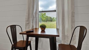 Una habitación con una mesa, dos sillas, un control remoto y una planta en maceta sobre la mesa.