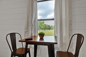 A room with a table and two chairs, a remote control, and a potted plant on the table. - Cates Cottage-8 Mins to Downtown Fred! (Fredericksburg)