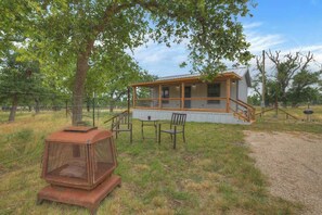 Eine rustikale Holzhütte mit Veranda, umgeben von Bäumen und einem eingezäunten Bereich.