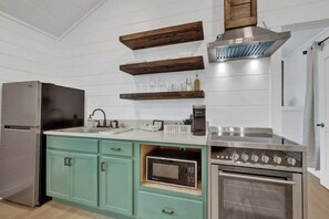 Eine moderne Küche mit Edelstahl-Kühlschrank, eingebautem Backofen, Mikrowelle und einer Kaffeebar.