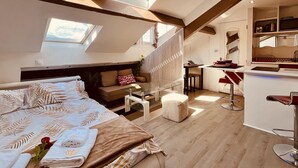 Un dormitorio tipo loft moderno con una cama grande, una zona de estar y una kitchenette.