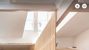 Una sala de estar moderna con una mesa de centro de vidrio, un separador de madera y un sofá con un cojín rojo.