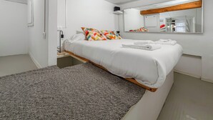 Un dormitorio moderno con una cama, una mesita de noche, un espejo y una alfombra estampada.