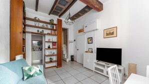 Una sala de estar moderna con un sofá, televisor y estantería.