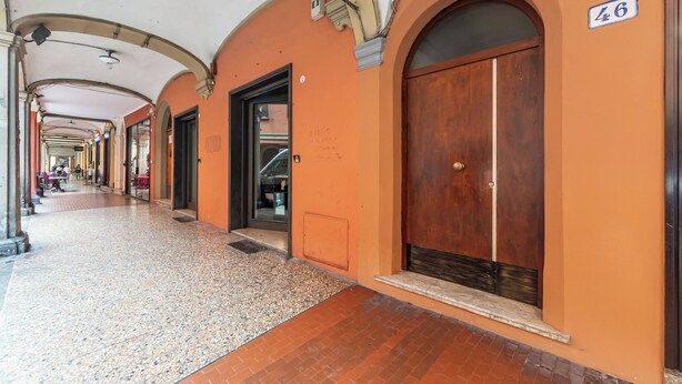 Un pasillo con arcos, suelo de baldosas y un cartel que indica la habitación número 46.