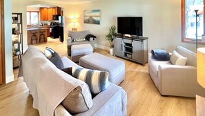 A modern living room with a sofa, ottoman, and a TV stand. - Spacious Spring Lake Retreat • Beach Access • Sleeps 8 • Family & Pet Friendly (Spring Lake)