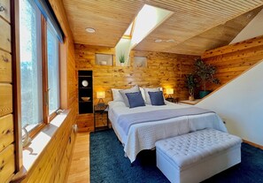 A cozy wooden cabin bedroom with a bed, bedside tables, a clock, and a skylight. - Spacious Spring Lake Retreat • Beach Access • Sleeps 8 • Family & Pet Friendly (Spring Lake)