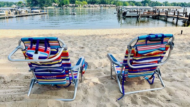 Two striped beach chairs facing a marina with boats and a dock. - Spacious Spring Lake Retreat • Beach Access • Sleeps 8 • Family & Pet Friendly (Spring Lake)