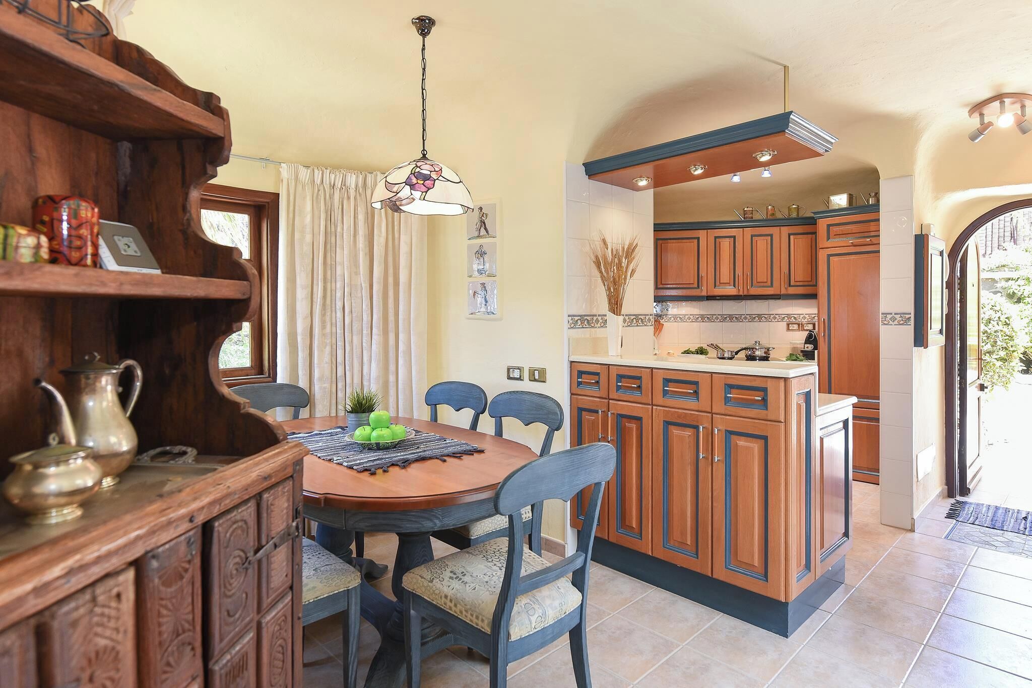 A kitchen with wooden cabinets, a central island, and a dining area with a table and chairs.