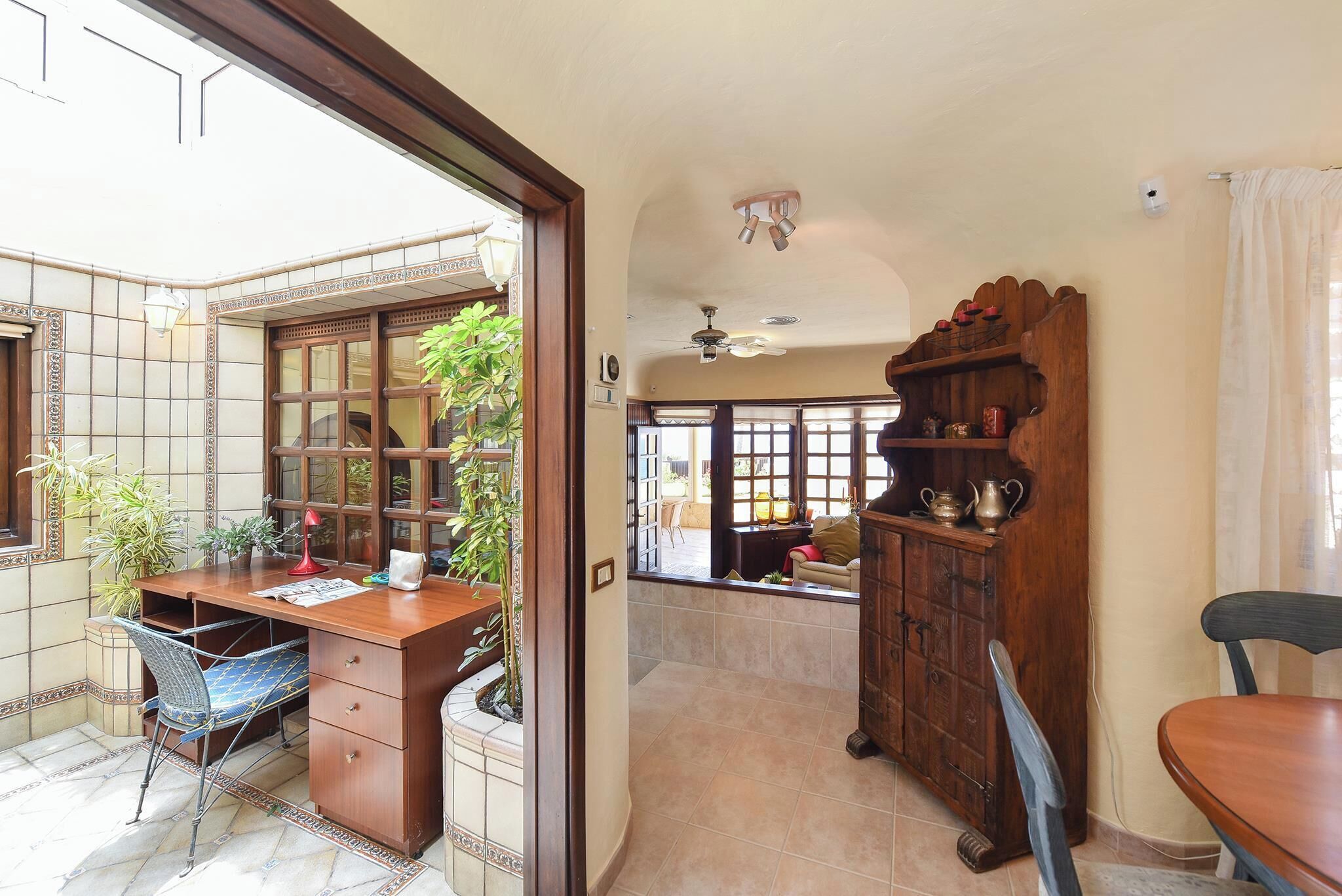 Una habitación con un escritorio de madera, una silla, un armario y un ventanal.
