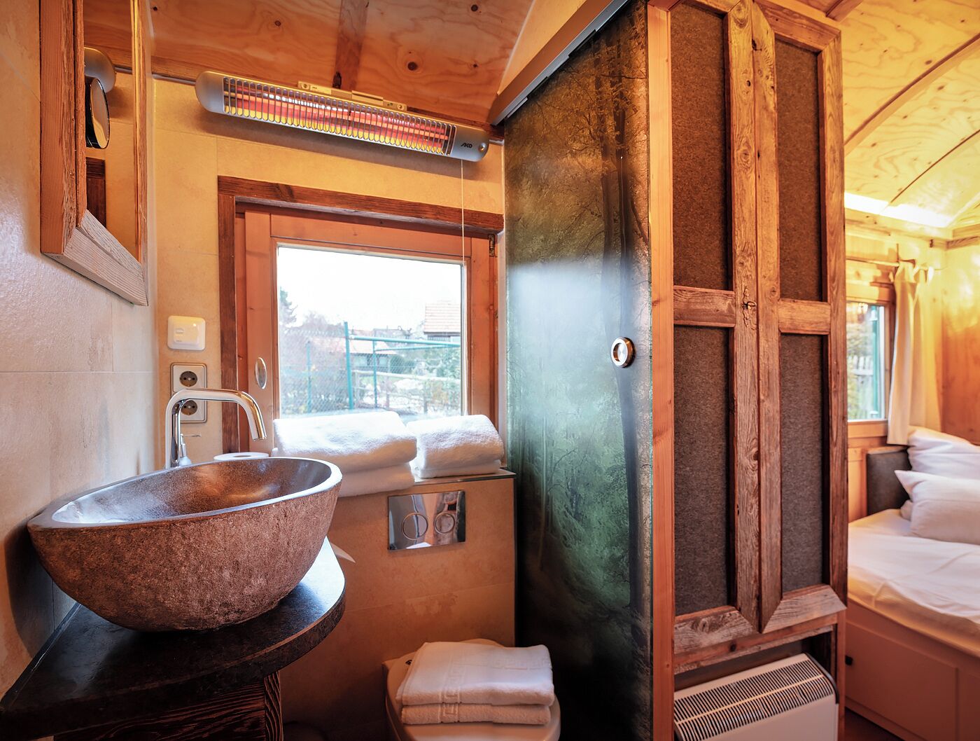 Un baño pequeño con un lavabo de piedra, una ventana y un armario de madera.