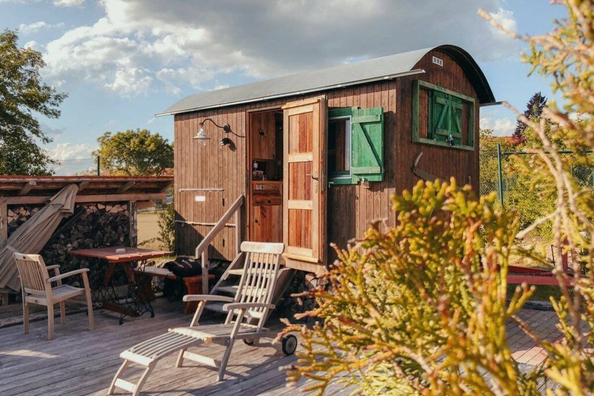 A wooden cabin with a porch, a table, and chairs.